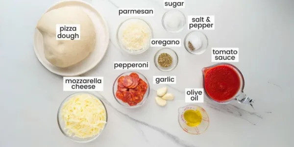 Ingredients for making pepperoni pizza including dough, sauce, cheese, and pepperoni